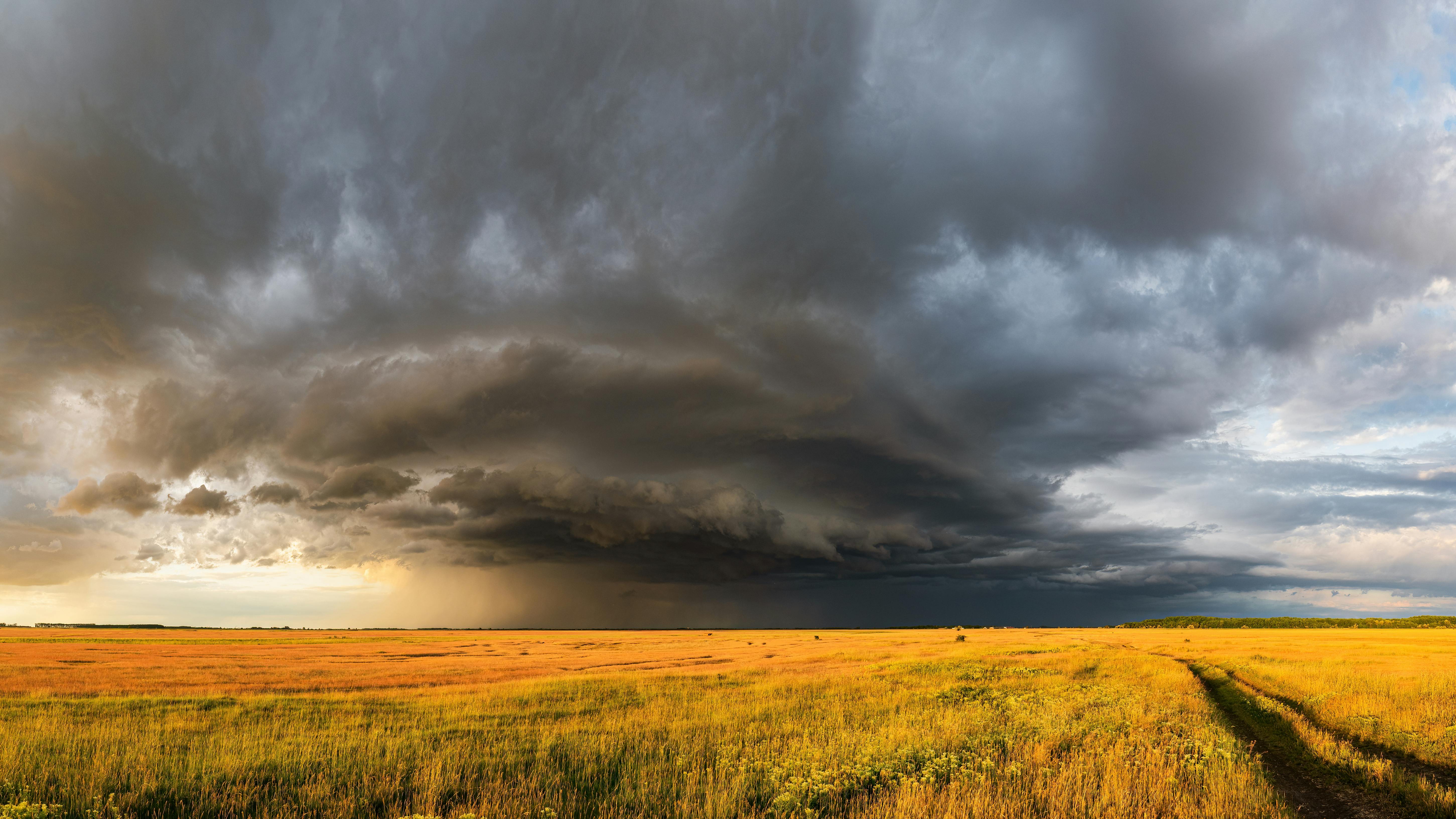 Câmp vast sub nori de furtună impunători, demonstrând fenomene meteorologice dramatice