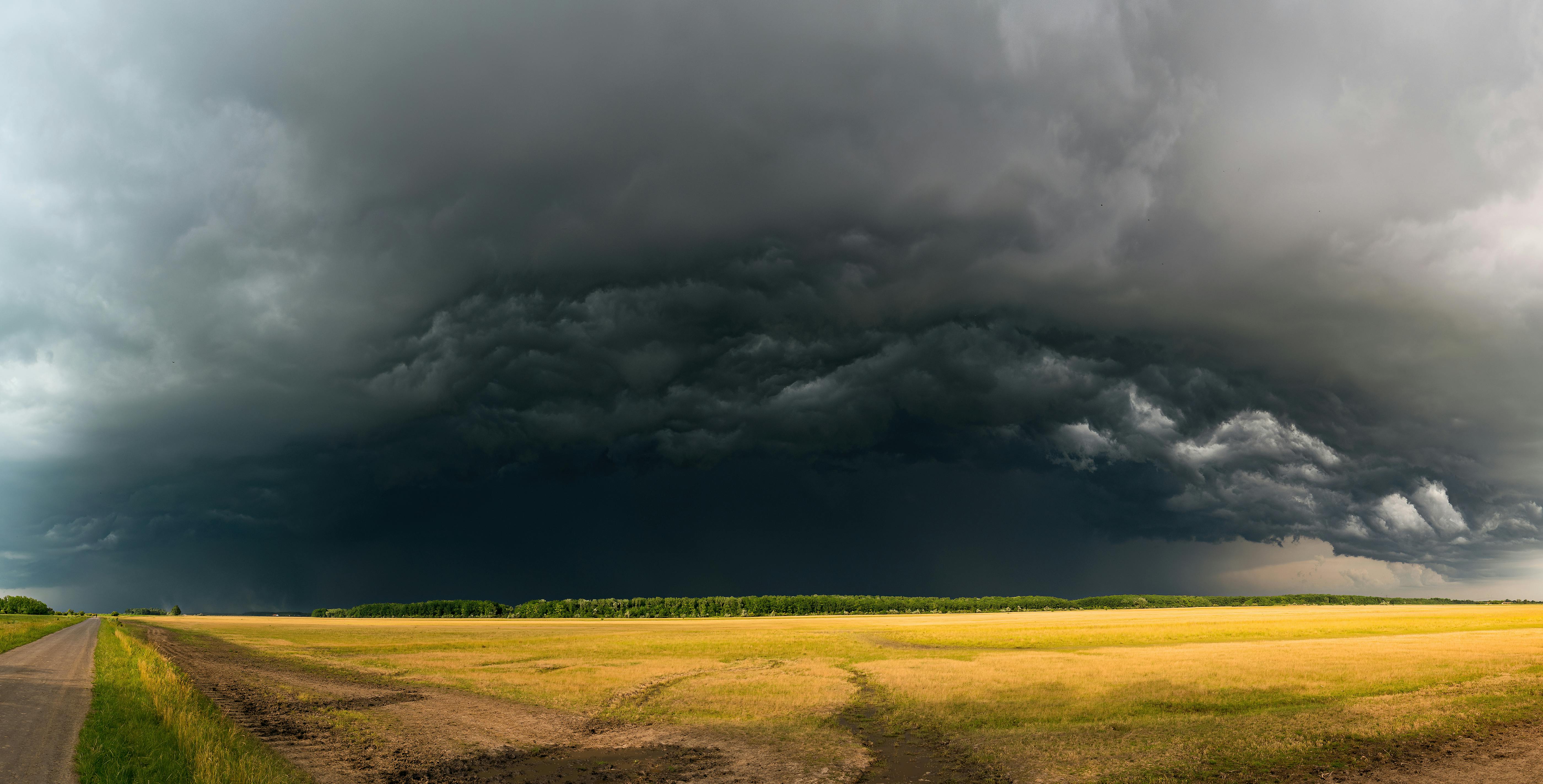 Photograph of storm clouds brewing over an expansive rural field, capturing the essence of weather dynamics.