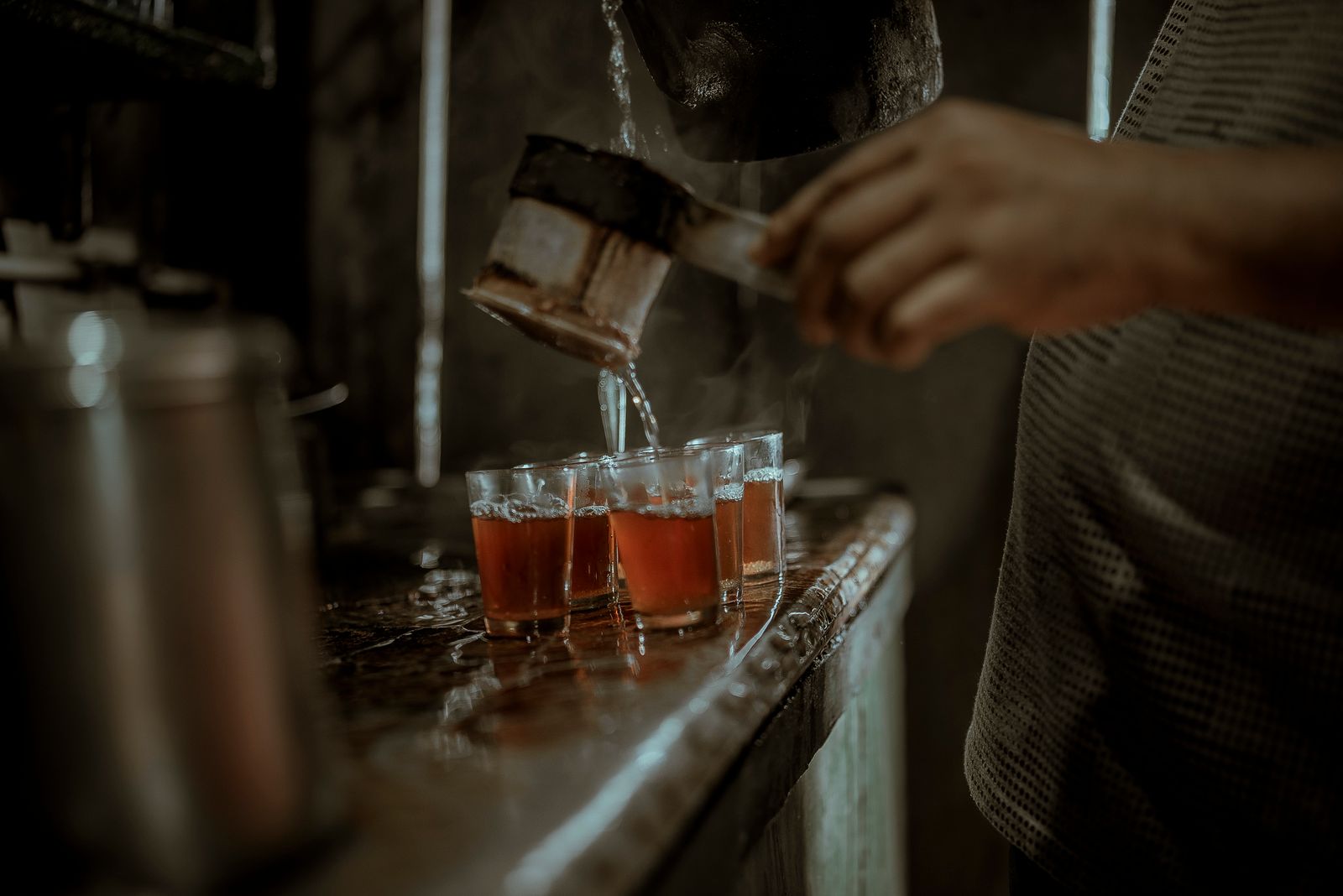 Tea poured into a row of small glasses on a tea shop counter in Darjeeling, the liquor deep amber