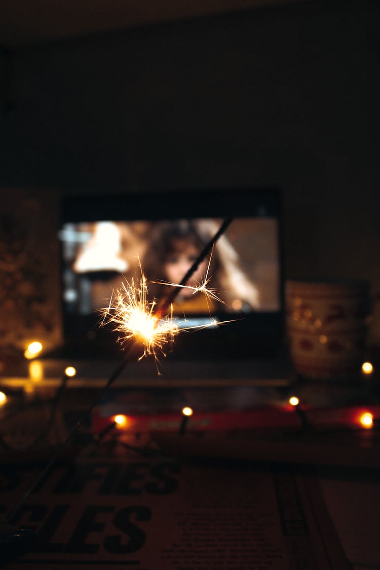 Lit Sparkler In Front Of Screen Displaying Movie