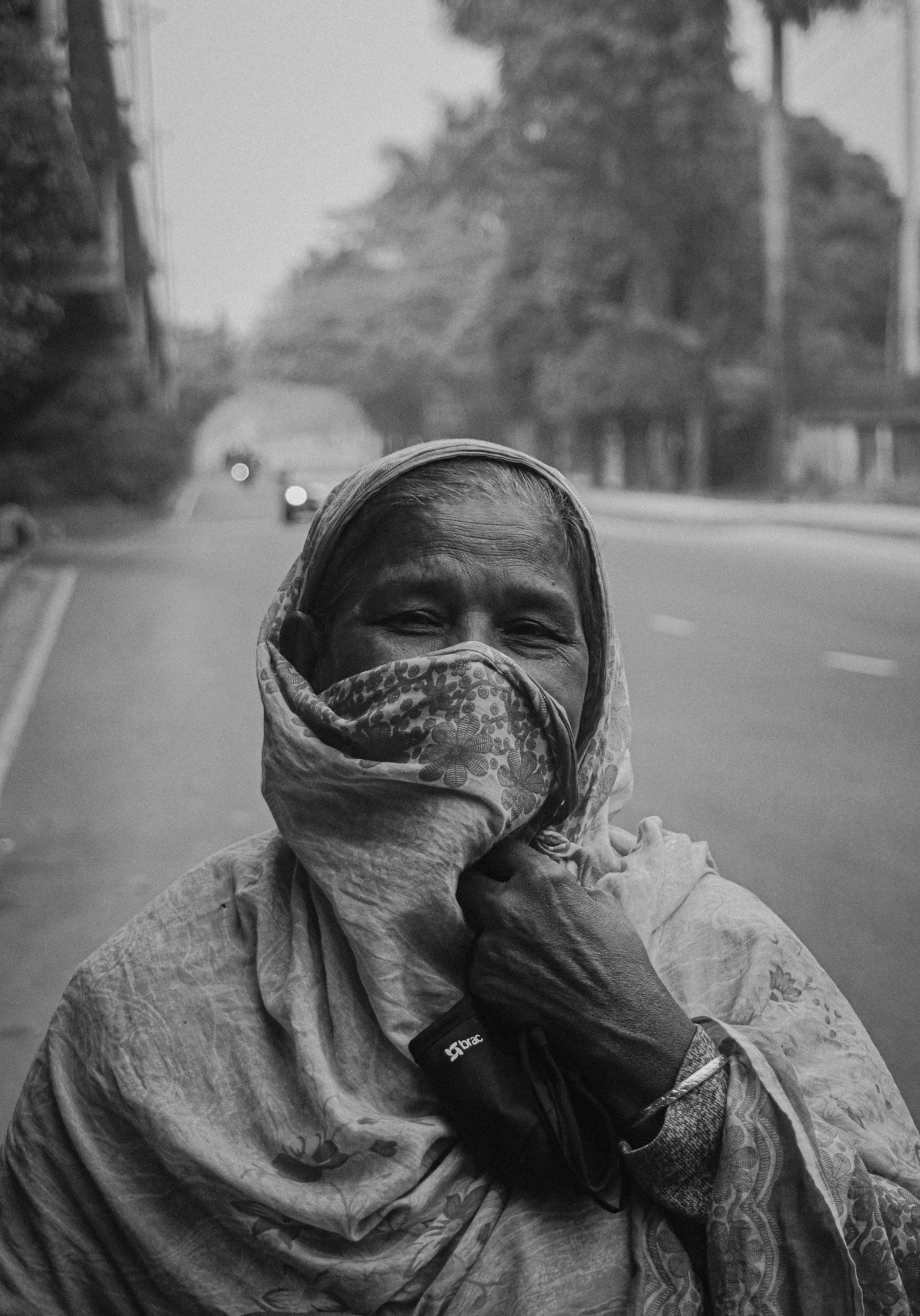 Portrait of an elderly woman standing on a road in Dhaka, Bangladesh, wrapped in a shawl.