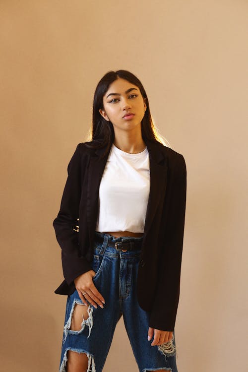 Studio Shot of a Young Woman in Ripped Jeans, White Shirt and Black Jacket 