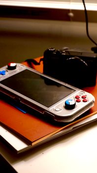 Close-up of a portable gaming console and camera on an indoor desk setting.