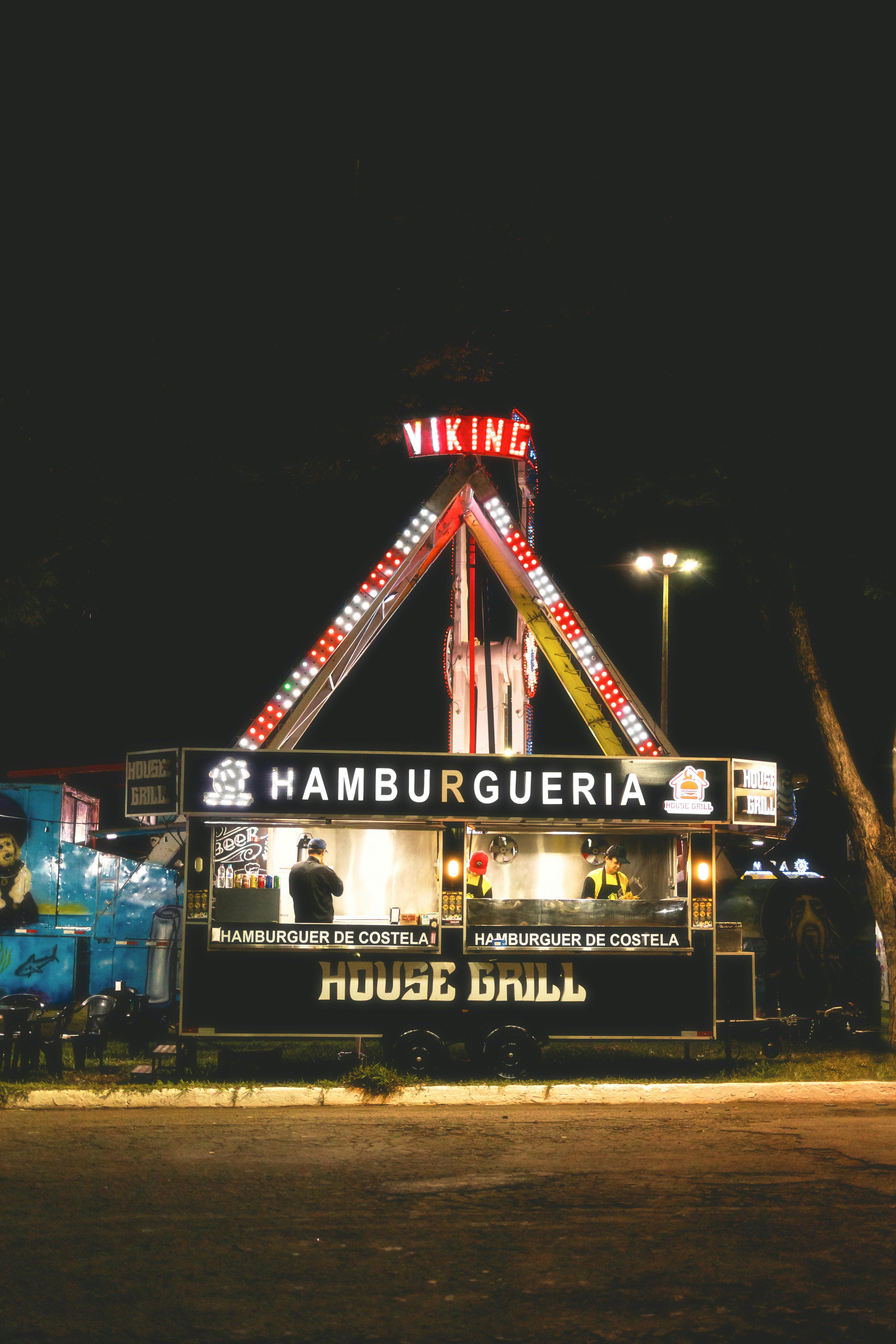 Illuminated hamburger food stall at night in a Brazilian amusement park, reflecting vibrant fairground atmosphere.