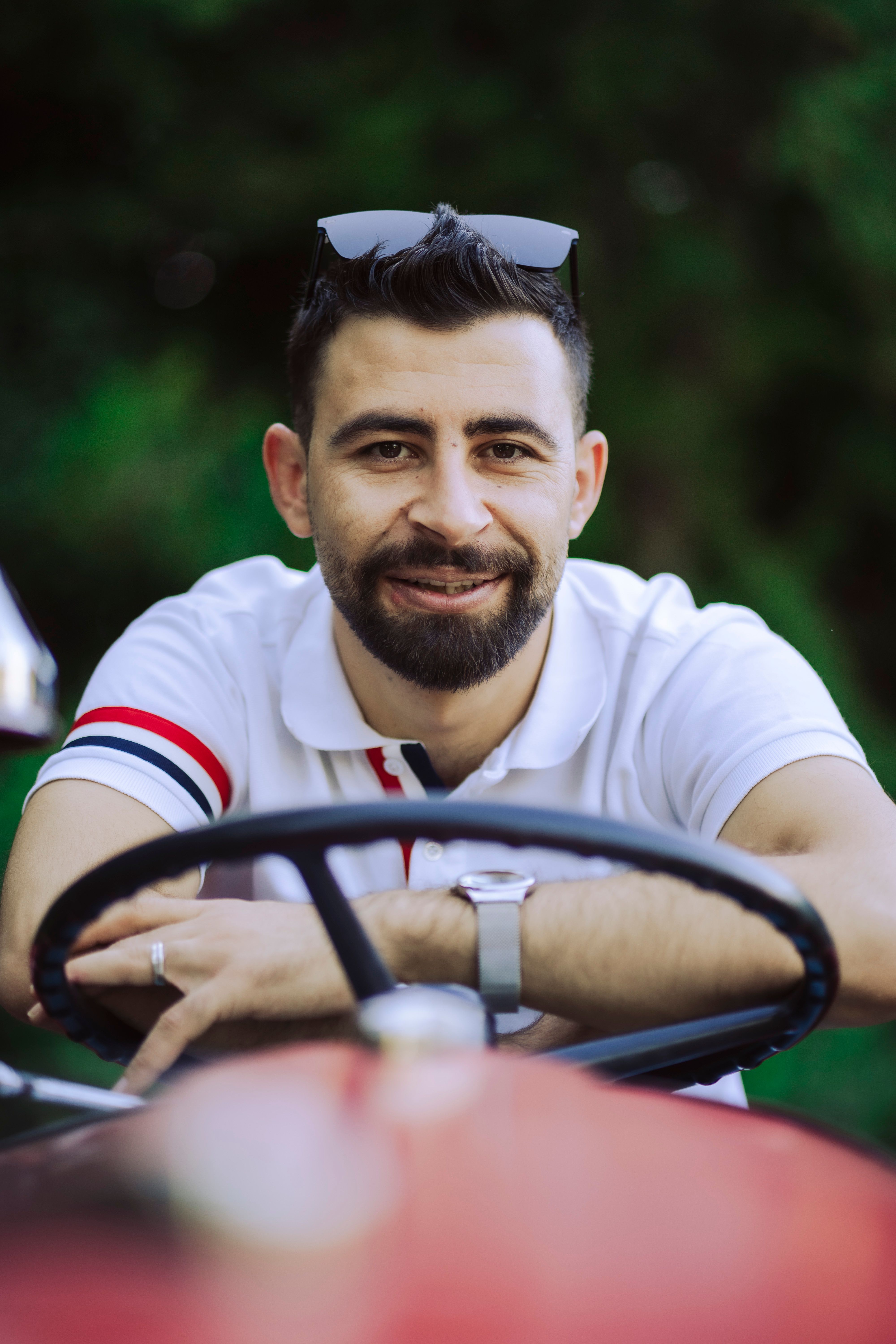 Portrait of a bearded man in sunglasses sitting on a tractor outdoors.