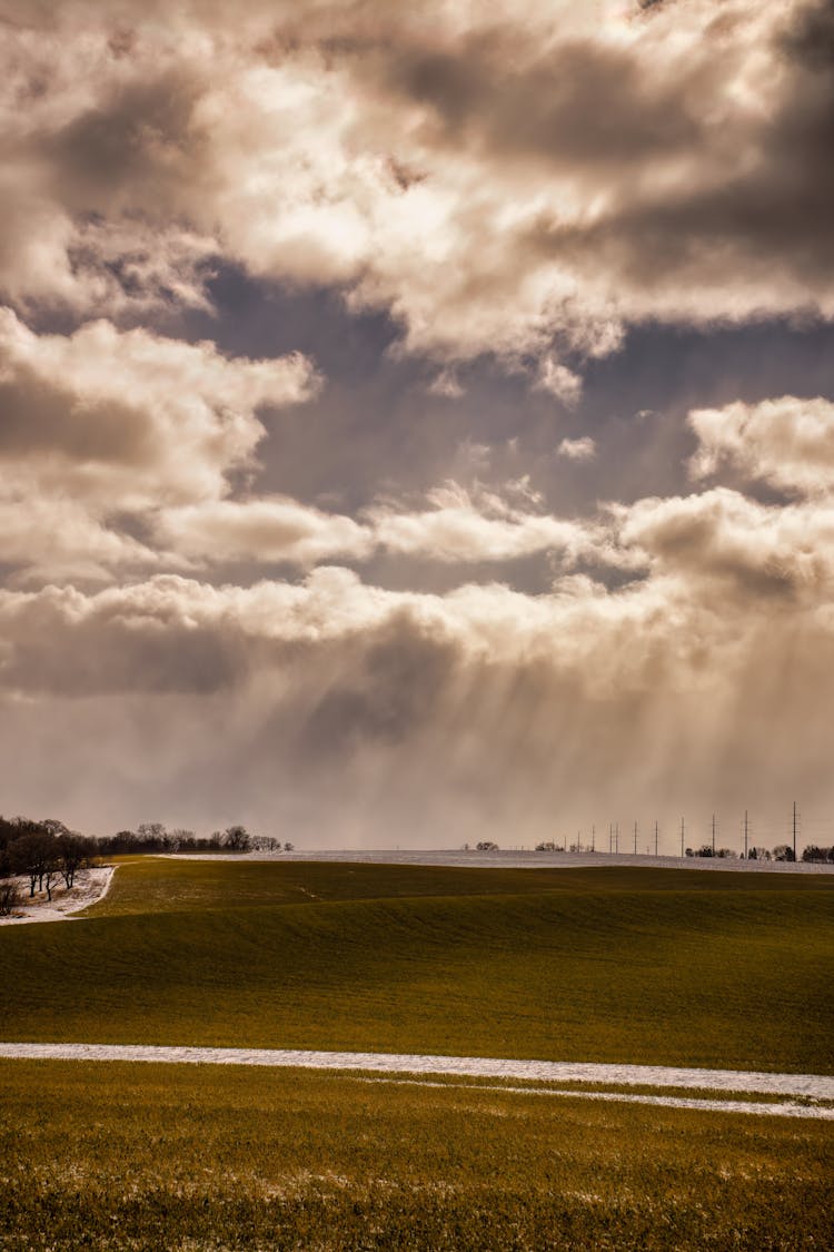 Sun Shining Through Clouds Onto Field