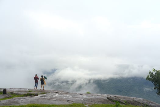A couple enjoys a misty view of the valley in OR, India. Perfect for landscape and travel themes.