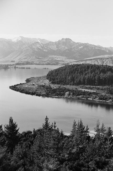 Stunning monochrome aerial view of a serene lake surrounded by mountains and dense forest.