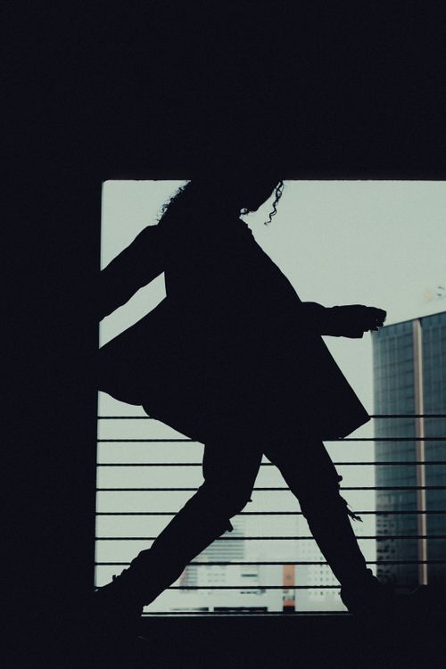 Free Dramatic silhouette of a woman walking past railings in a cityscape setting. Stock Photo