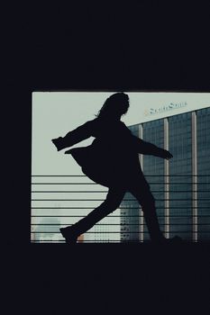 Dynamic silhouette of a woman posing against a city building background for urban lifestyle concept.