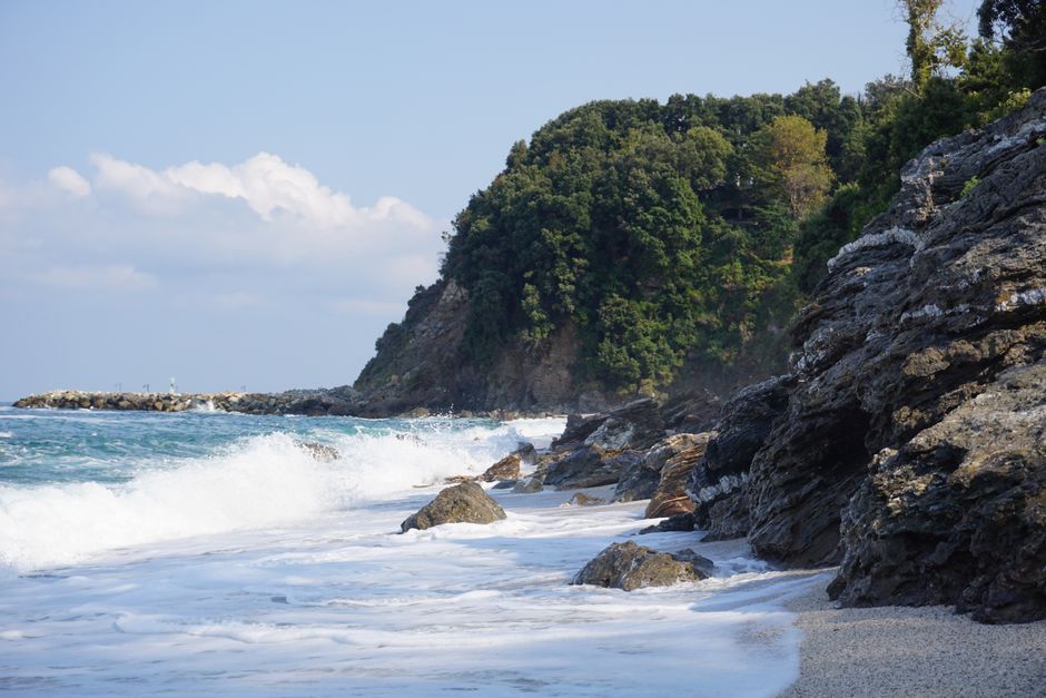 Beautiful rocky coastline with waves crashing onshore under a blue sky.