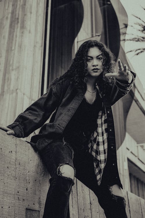 Brunette Woman in Dark Jacket Posing by Concrete Wall