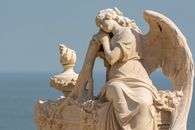 A tranquil angel sculpture rests peacefully with the ocean as a backdrop, symbolizing serenity and reflection.
