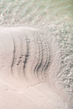 Close-up of rippled sand and gentle waves on a beach in Maafaru, Maldives.