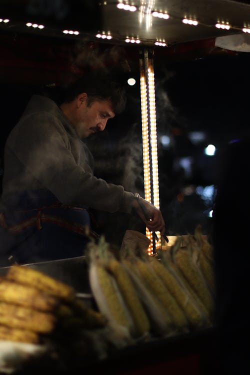 Man Selling Corn from Stand at Night