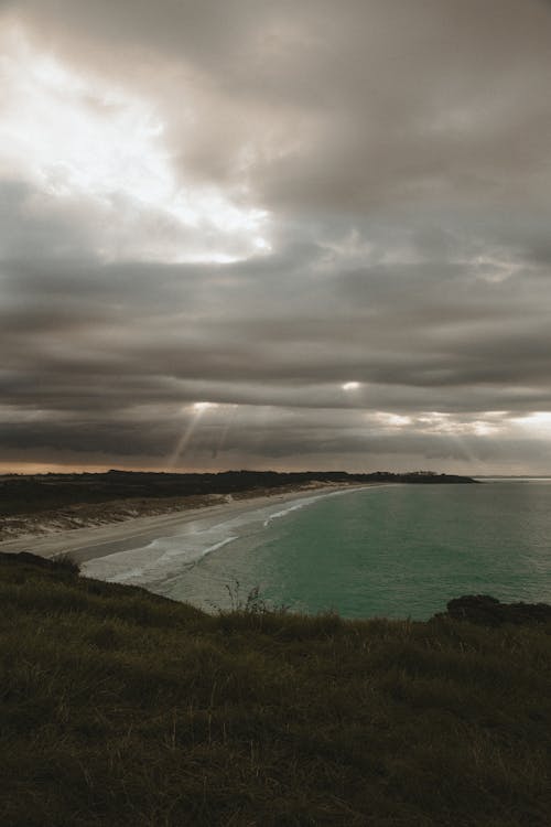 Foto profissional grátis de cênico, céu nublado, costa