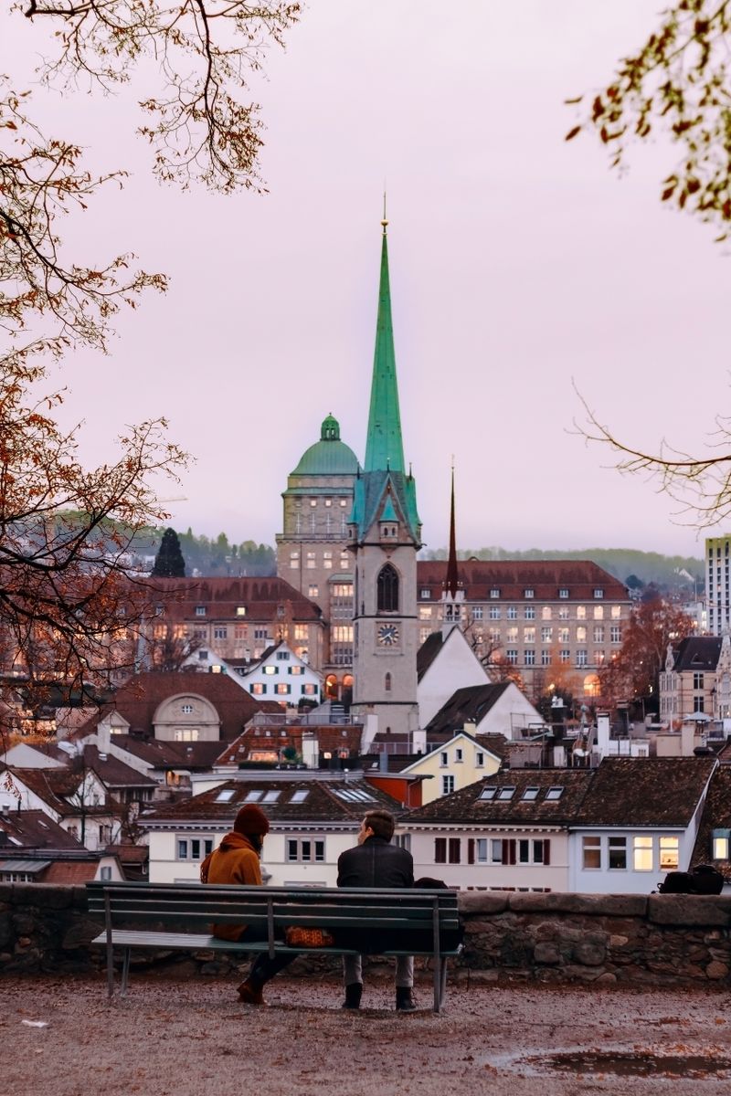 People sitting on a bench at Lindenhof viewpoint overlooking Zurich