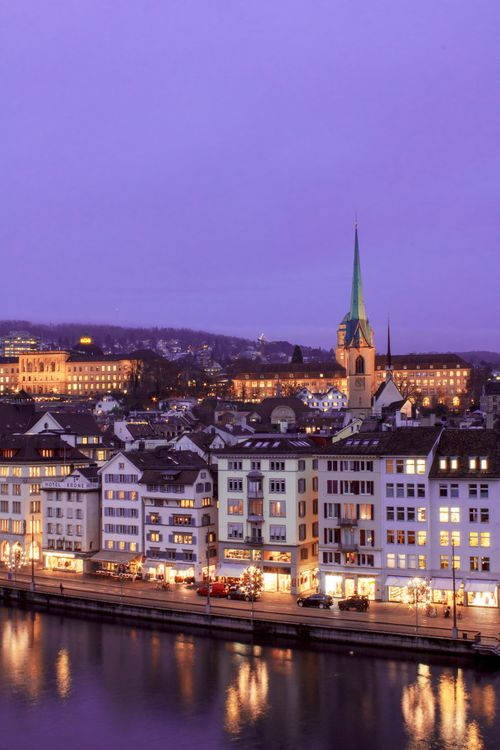 Free A captivating aerial view of Zurich's illuminated cityscape at twilight with a purple sky. Stock Photo