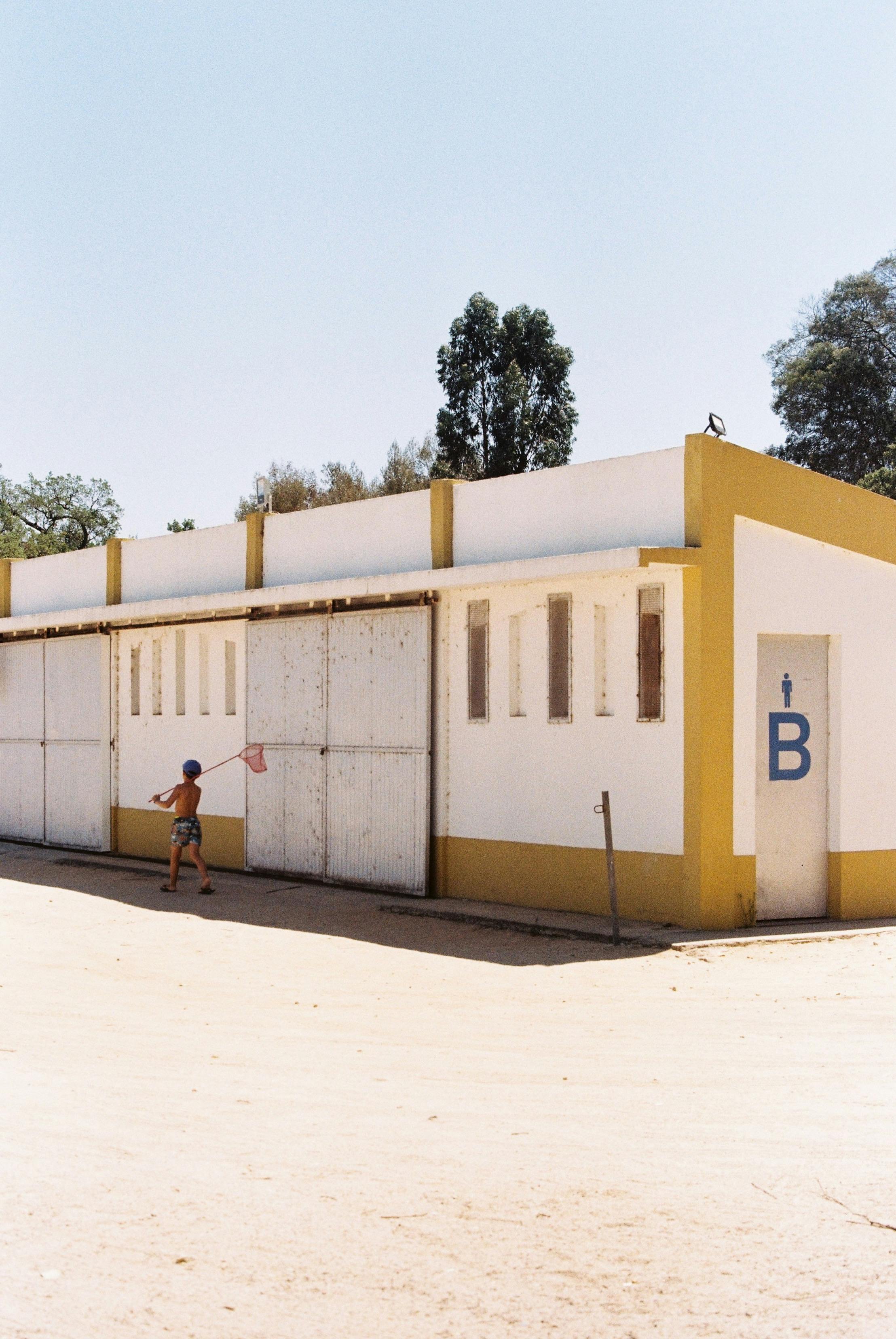 A child walks with a net by a colorful building in Montargil, Portugal.