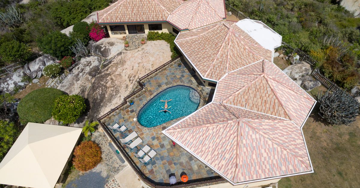 Aerial view of a luxury villa with a swimming pool surrounded by tropical greenery.