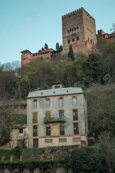 View of the Alhambra fortress above a historic building in Granada, Spain.
