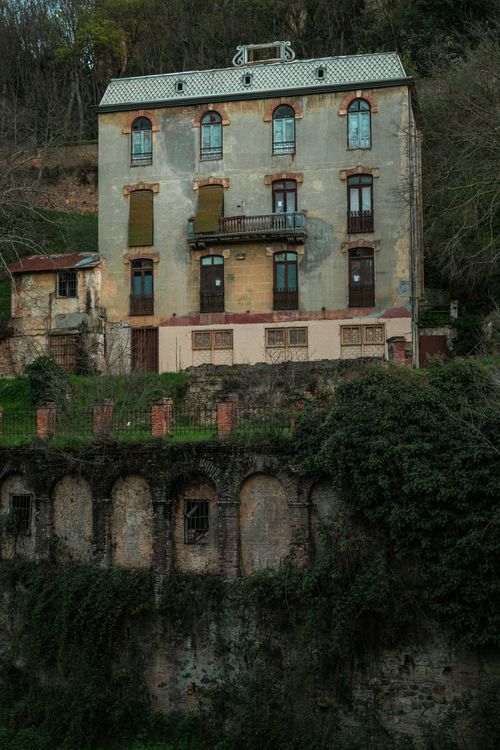 Free Old stone house with overgrown vegetation on a hillside. Stock Photo
