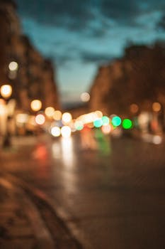 Blurred city street scene with colorful bokeh lights during twilight. Urban ambiance and evening glow.