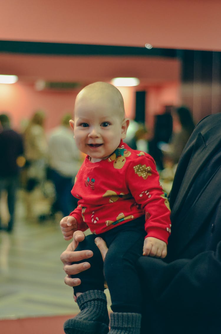 Man Holding A Little Baby In A Christmas Sweater 