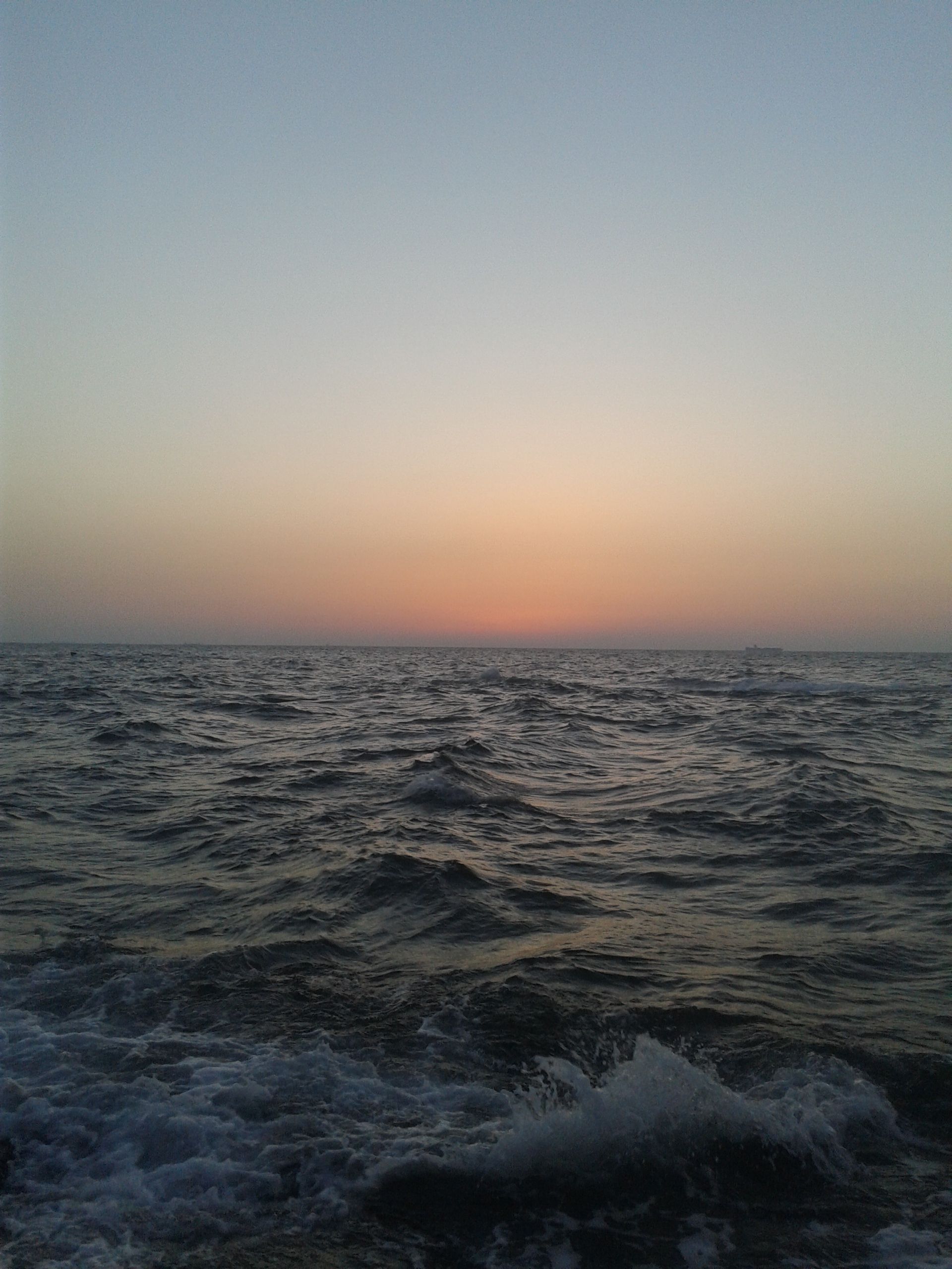 Fotomural Un paisaje marino tranquilo con olas suaves durante el atardecer, con un cielo colorido y una escena oceánica calma.