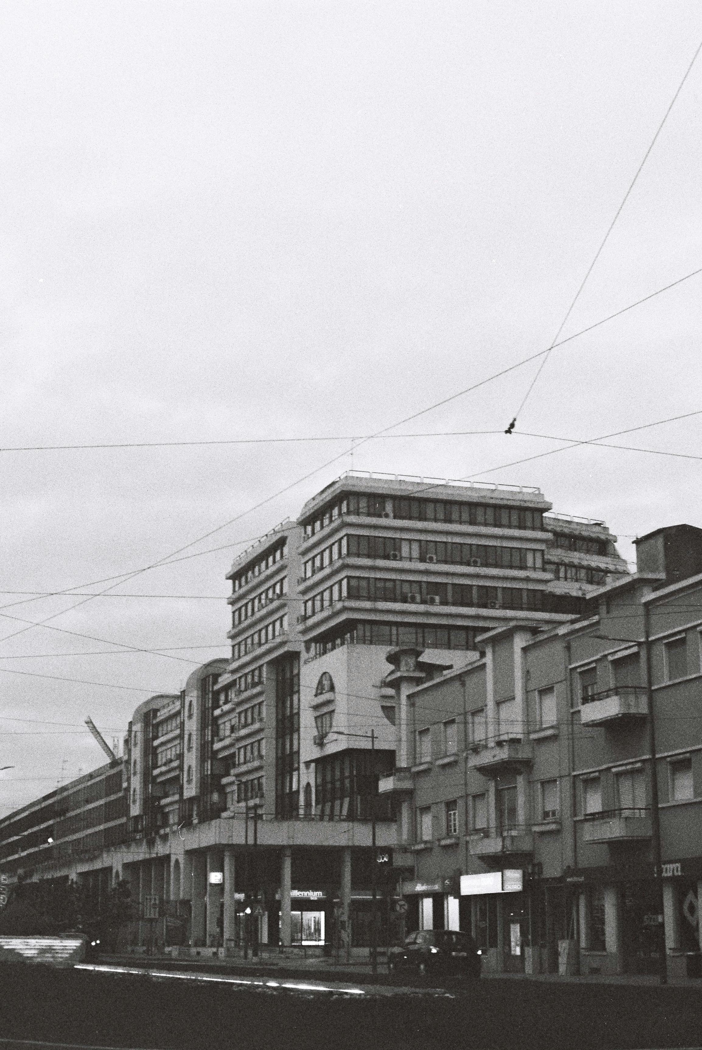 Monochrome photo of urban architecture in Coimbra, featuring apartment buildings and street activity.