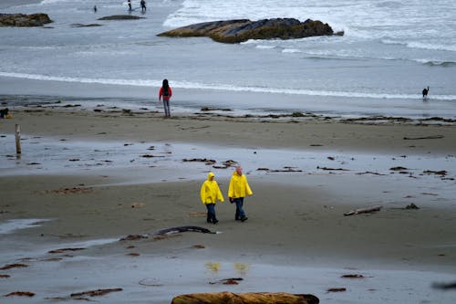 Couple in Yellow Raincoat Walking on Beach