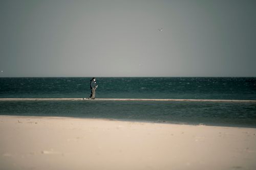 Free A solitary person walks on a deserted beach in Yangyang-gun, South Korea, under a cloudy sky. Stock Photo