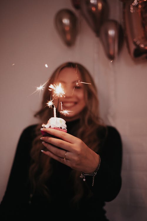 A Woman Holding a Cupcake with Sparklers