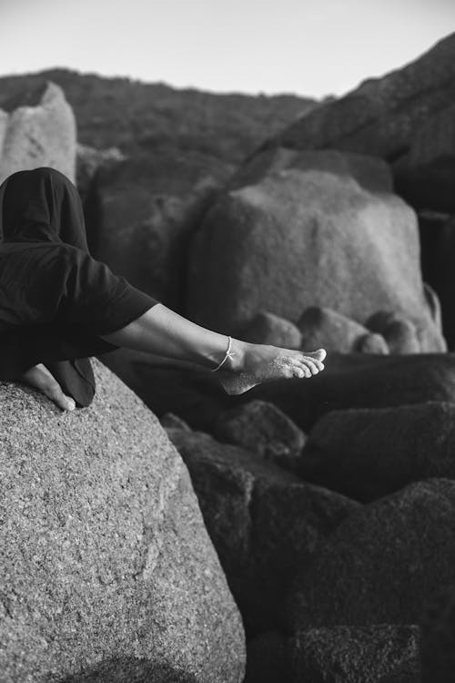 Black and White Photo of Foot Extending over Rock Edge