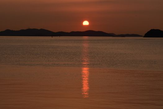 Golden sunset over a tranquil ocean with silhouetted islands, offering a serene and calming view.
