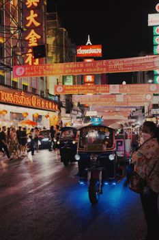 Colorful tuk-tuks and busy streets illuminate Bangkok's vibrant Chinatown at night.