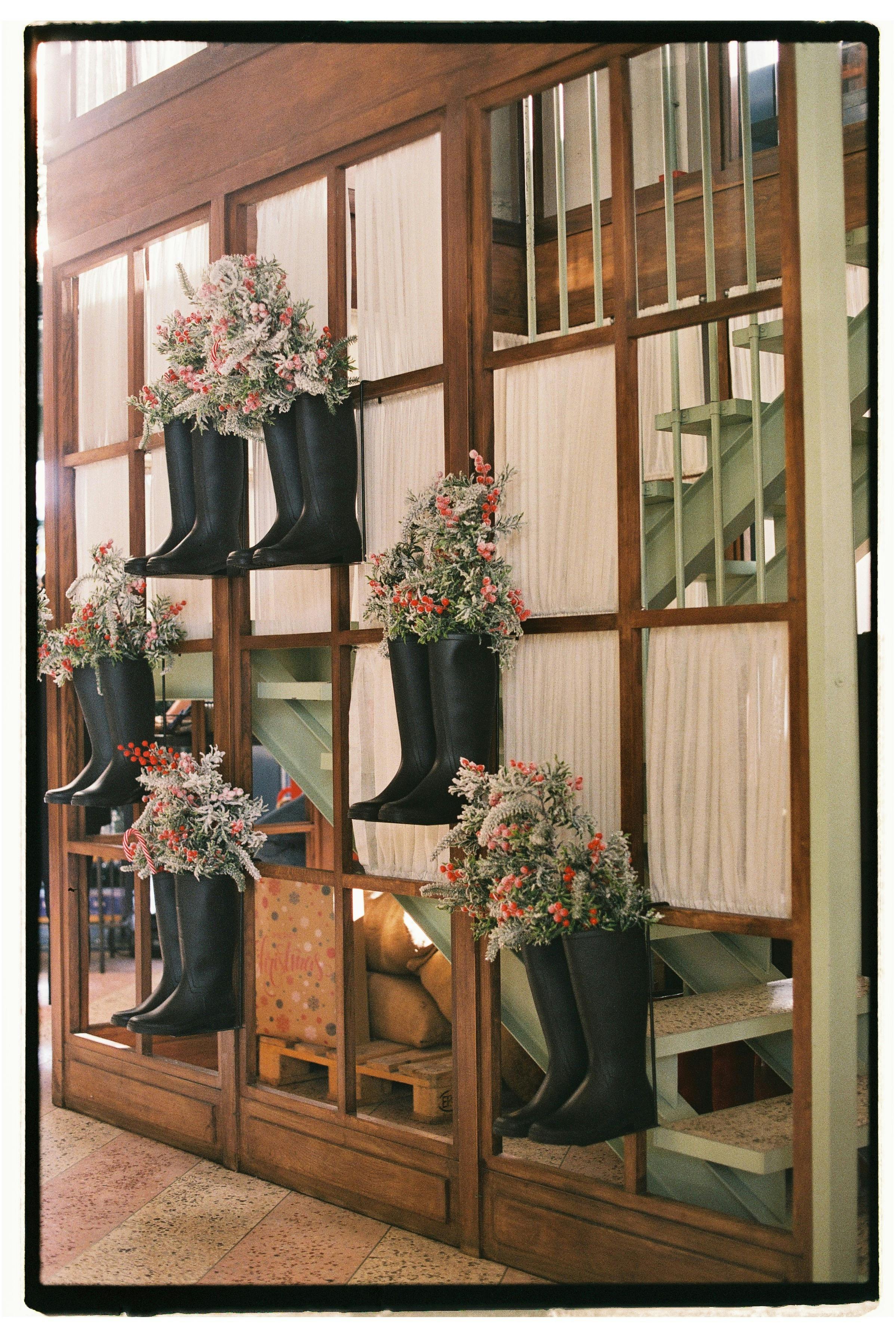 Charming indoor floral decor using black rubber boots as vases, captured in Tbilisi, Georgia.