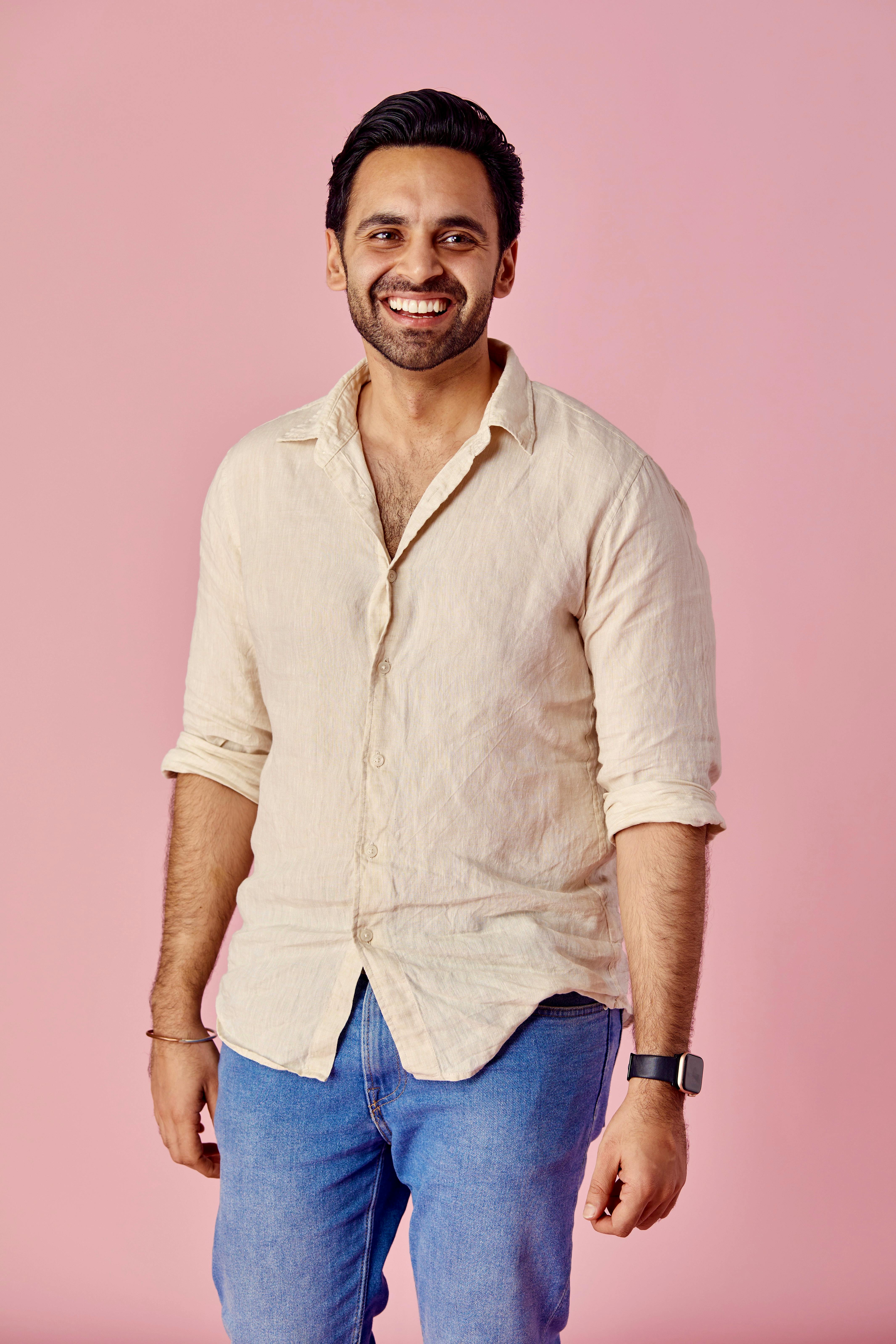 Happy man with beard and casual clothes smiling against pink backdrop.