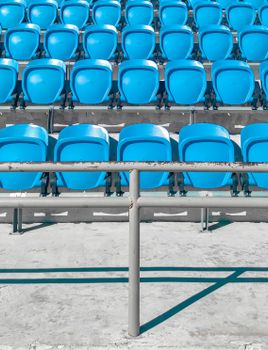 A row of vibrant blue seats in an empty stadium under clear skies in Subic, Philippines.