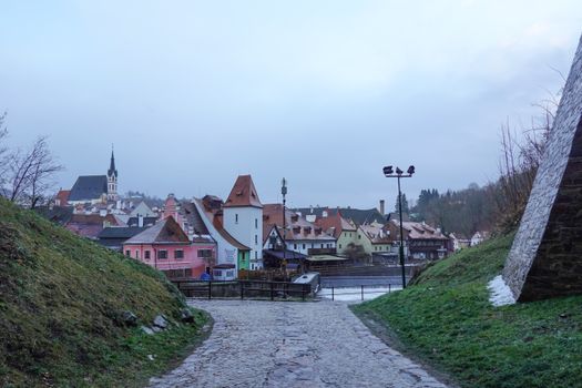Panoramic view of Český Krumlov with cobbled paths and historic architecture under an overcast sky.