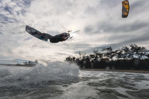 Free Thrilling kiteboarding stunt captured mid-air with water splash backdrop and expansive sky. Stock Photo