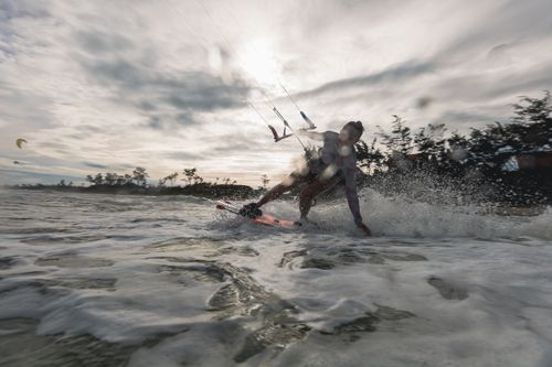 Free Dynamic image of a woman enjoying kiteboarding on the ocean. Captured at day. Stock Photo