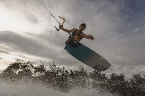 Free Thrilling low-angle shot of a kiteboarder performing a midair stunt on a cloudy day. Stock Photo