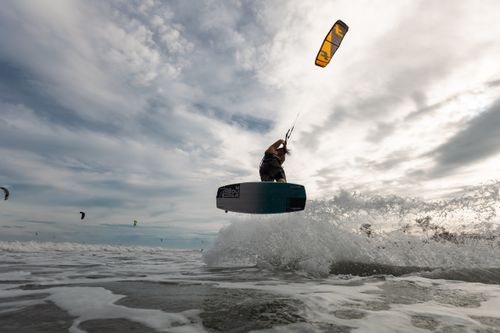 Free Exciting action shot of a kiteboarder in midair above ocean waves, showcasing skills and adventure. Stock Photo