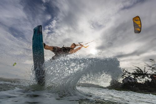 Free A thrilling kiteboarding moment captured with water spray and dramatic clouds. Stock Photo