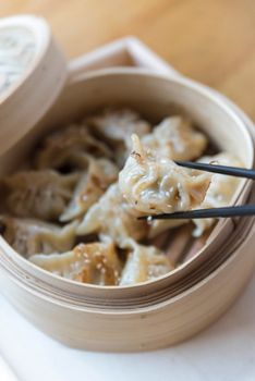 Close-up of savory steamed dumplings in a bamboo basket with chopsticks.