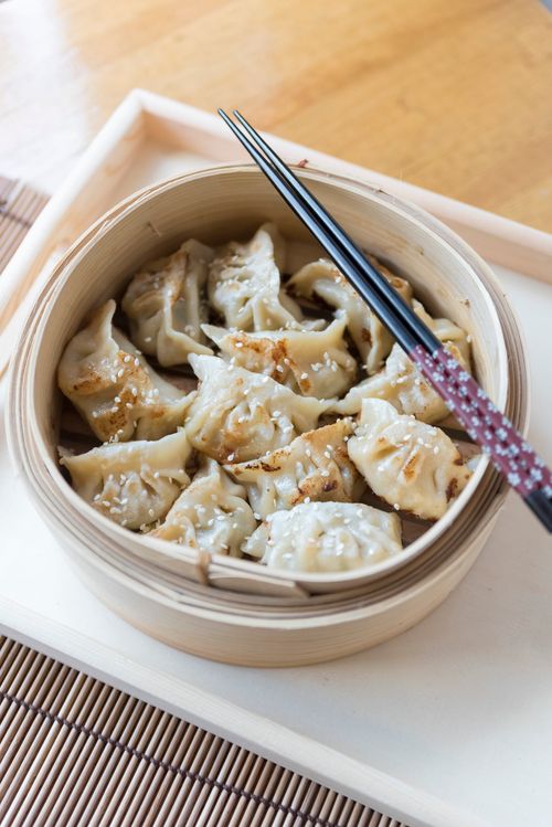 Free Close-up of delicious steamed dumplings in a bamboo basket with chopsticks on a table. Stock Photo