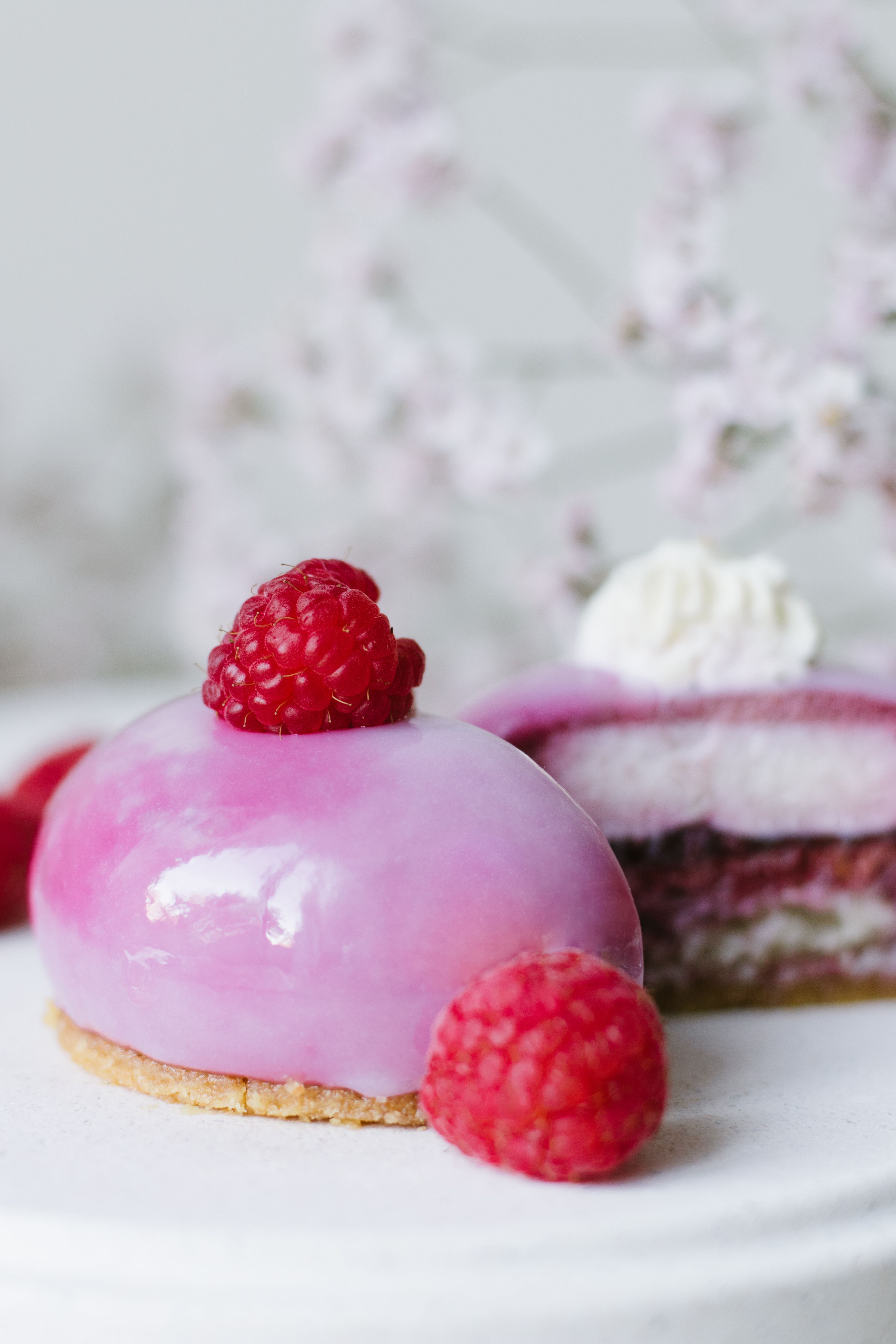 Close-up of a pink raspberry mousse dessert with fresh raspberries on top, showcasing delicate textures and colors.