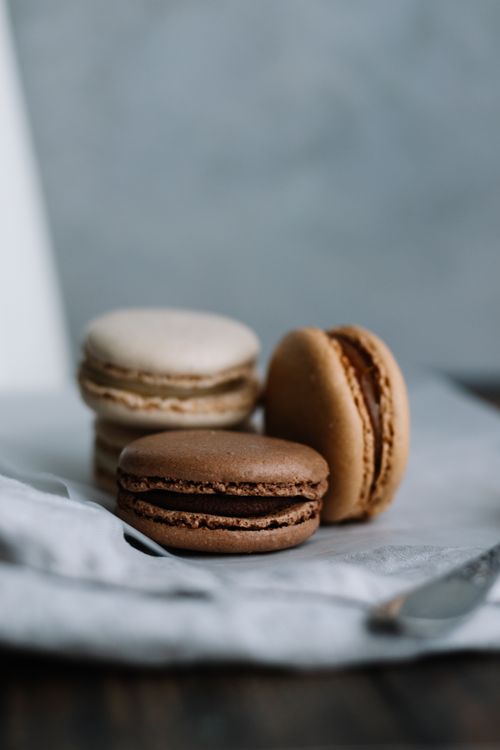 Free Close-up of delicious French macarons in brown, beige, and cream colors, perfect for dessert lovers. Stock Photo