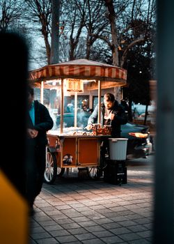 A street vendor selling snacks in the evening on a busy street in Istanbul, Türkiye.